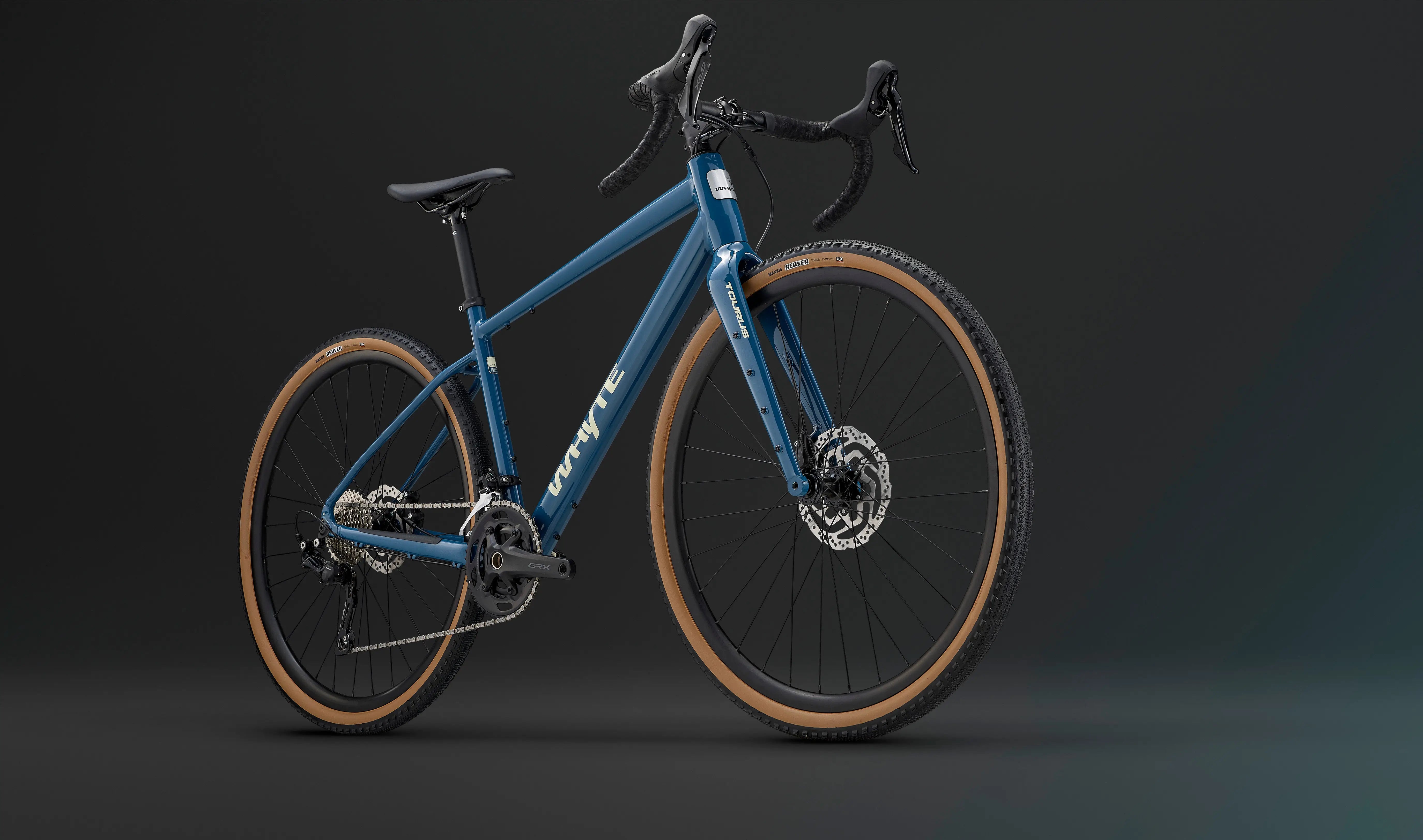 Front-side view of the blue Whyte Tourus Gravel Bike highlighting its rugged tires, disc brakes, and ergonomic drop bar design.