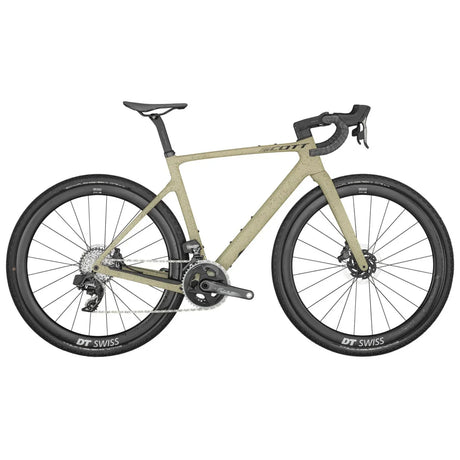 The Scott Addict Gravel 10 is a beige gravel bike featuring drop handlebars, disc brakes, and wide DT Swiss tires. It boasts a sleek, angular frame design with a compact rear triangle. Equipped with a SRAM drivetrain, this bike is built for both versatility and durability on mixed terrains.