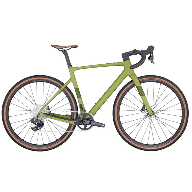 The Scott Addict Gravel 30 is a sleek, olive green road bike featuring drop handlebars, a brown saddle, and brown-rimmed tires. It boasts a modern design with disc brakes and a black drivetrain that includes a rear derailleur and gear cassette. Its frame is both sturdy and streamlined.