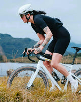 Cyclist riding a white Cervelo Aspero gravel bike on a track beside a loch