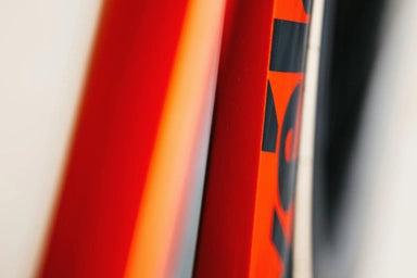 Close-up of Cervélo S5 Red XPLR AXS 1's down tube and front wheel, showing bold branding and high-gloss red carbon finish.