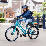 A child, sporting a helmet, rides the Frog City 61 Kids Hybrid Bike by Frog down a paved path in an urban setting. The bike's 8-speed gear system and lightweight frame make for an easy ride as they smile, clad in a blue hoodie and jeans. Buildings and a bridge are visible in the background on this sunny day.