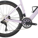 Close-up of violet pink electric road bike drivetrain with rear derailleur, chain, and carbon fiber wheels.