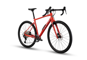A red gravel bicycle with black components, drop handlebars, and a black saddle, shown from a three-quarters angle on a white background with a soft shadow.