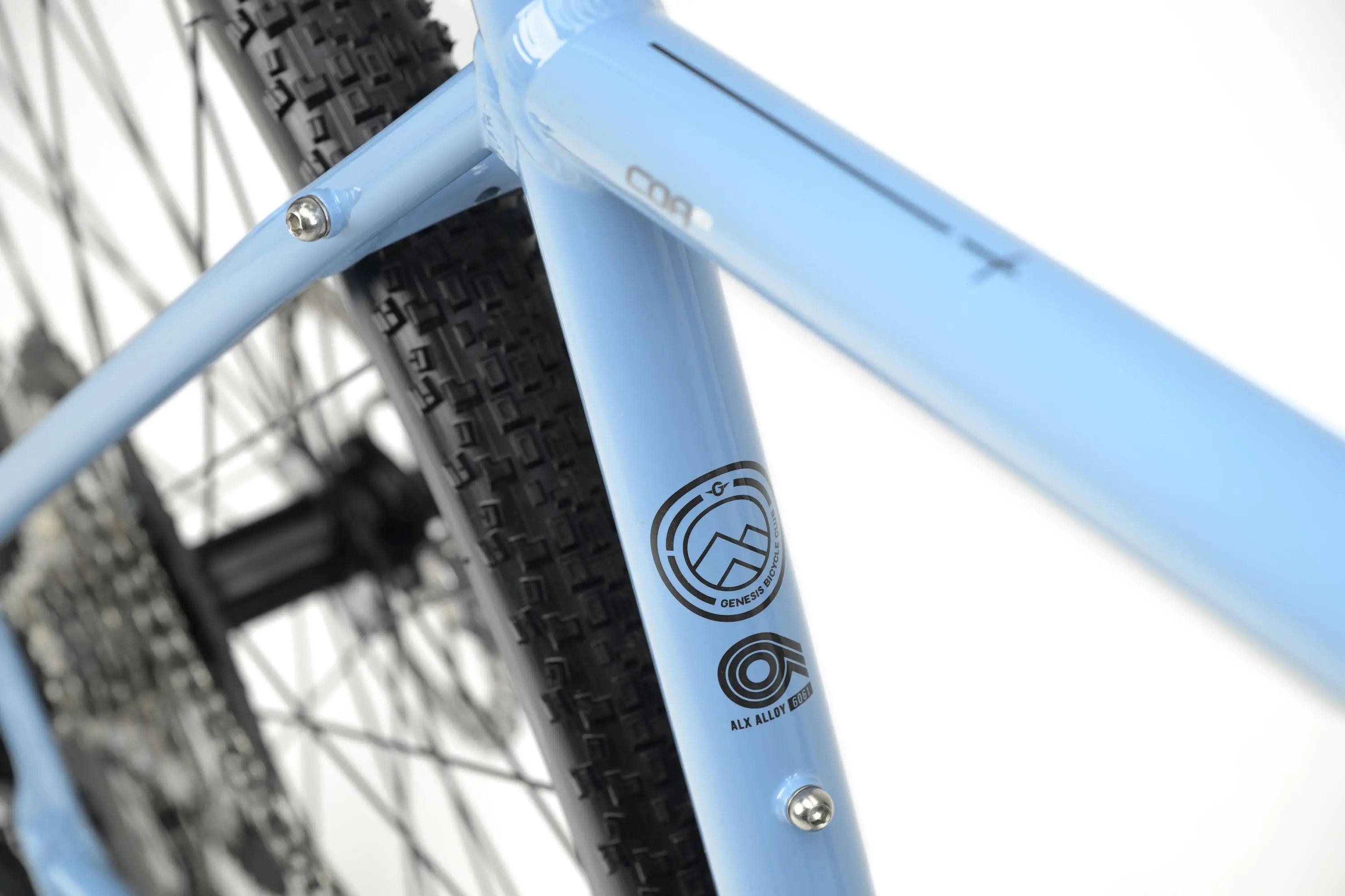 Close-up of light blue Genesis CDA 10 gravel bike frame showing logo and rear tire tread.