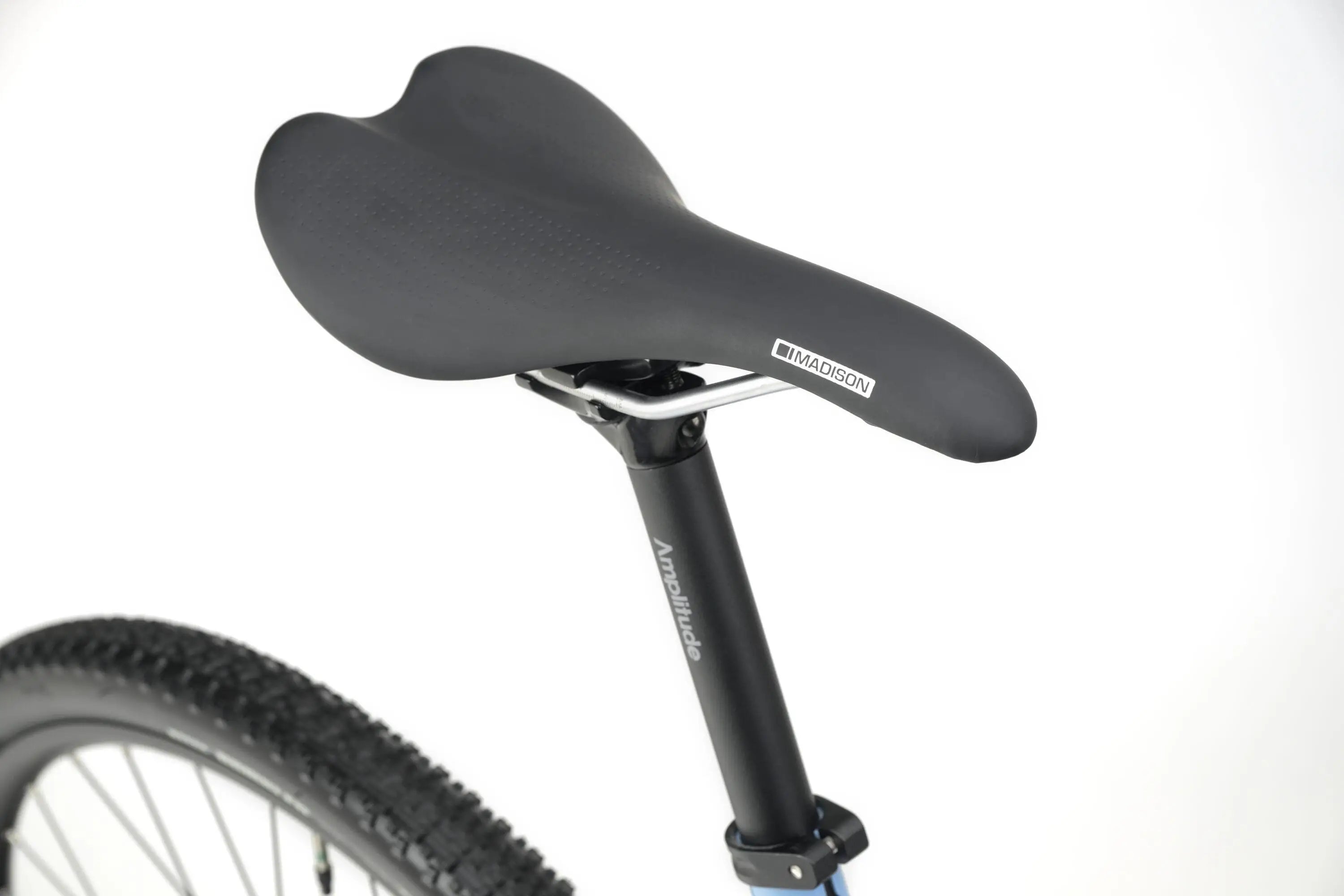 Black ergonomic saddle on Genesis CDA 10 gravel bike with blue frame and knobby tire visible.