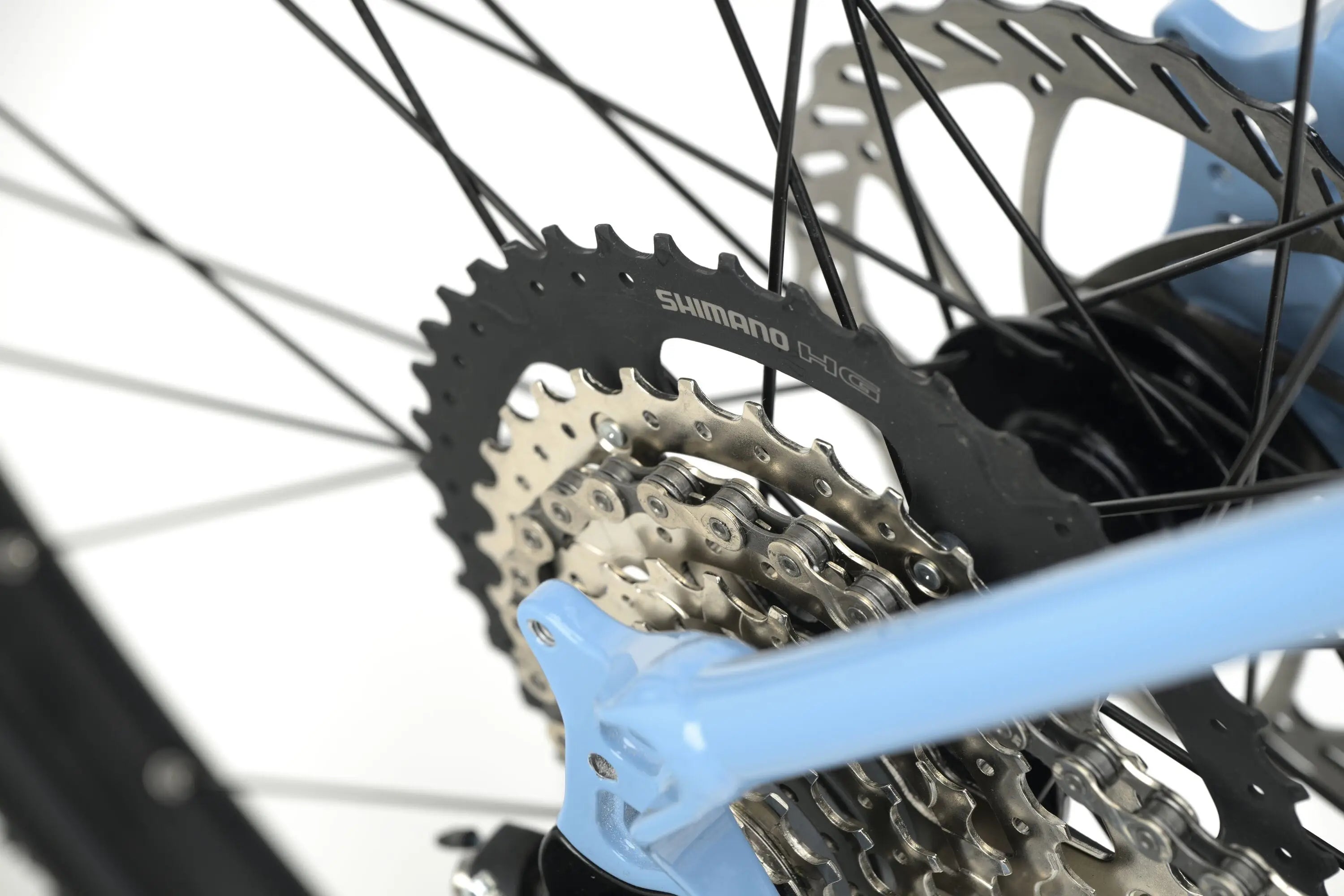 Close-up of blue Genesis CDA 10 Gravel Bike rear gear cassette and spokes with disc brake rotor.