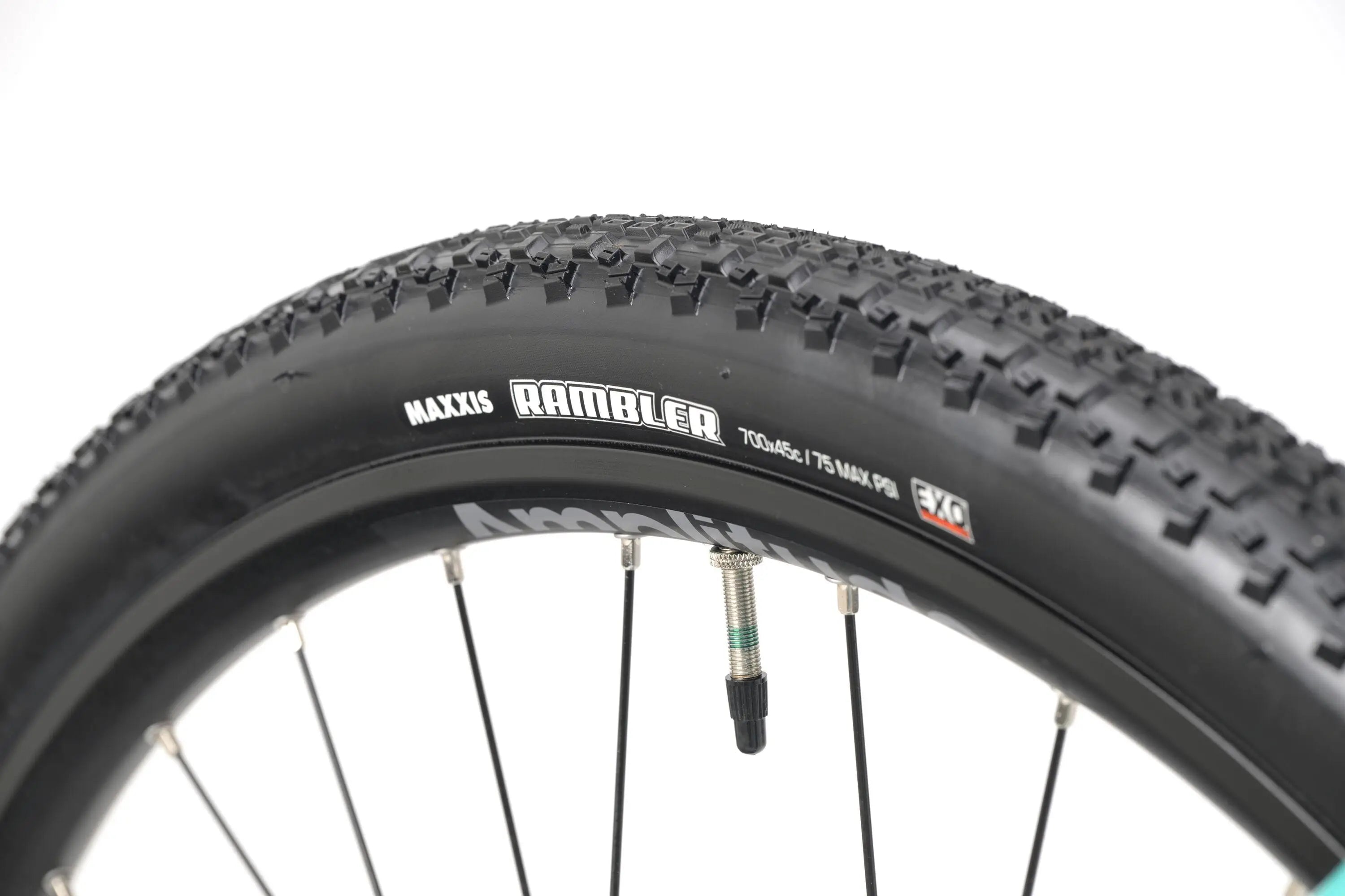 Maxxis Rambler knobby tire with thick tread on a black rim and spokes.