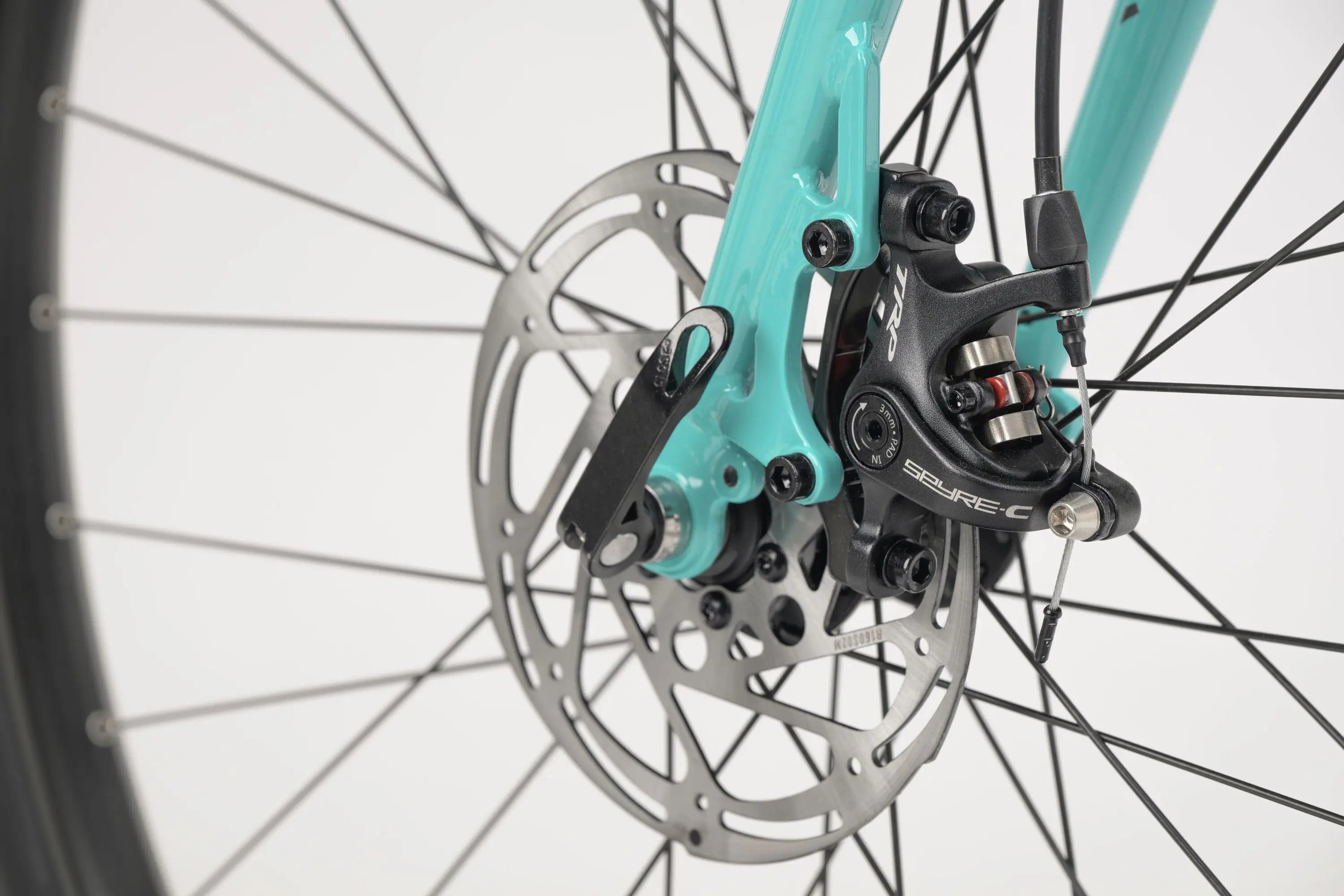 Close-up of teal gravel bike front disc brake and rotor with black caliper and spokes.