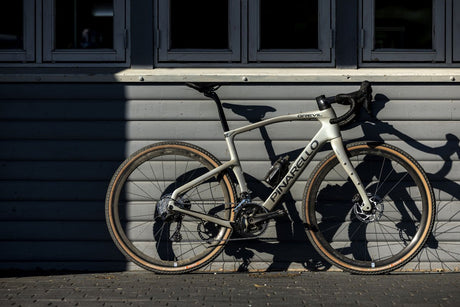 White bicycle with 'Pivotal' branding leaning against a gray building.