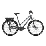 A side view of a dark gray Gazelle Medeo T9 HMB Low Step Electric Hybrid Bike showcasing a step-through frame, rear rack, fenders, and a Bosch motor mounted beneath the rear rack. This bike is equipped with Shimano disc brakes and a kickstand, with the Gazelle brand name prominently displayed on the frame.