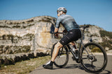 Man in gray cycling jersey and black shorts riding black Merida Scultura Endurance 9000 road bike on mountain path.