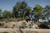 Rider on a Merida Mission 7000 gravel bike at speed on a dusty track, background blurred