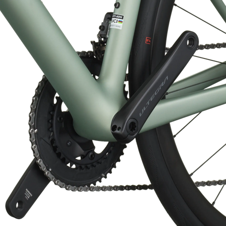 Close-up of a bicycle chain and gear system on a light green frame.