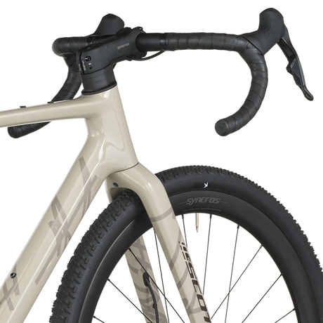 Close-up of a bicycle with beige frame and black tires on a white background