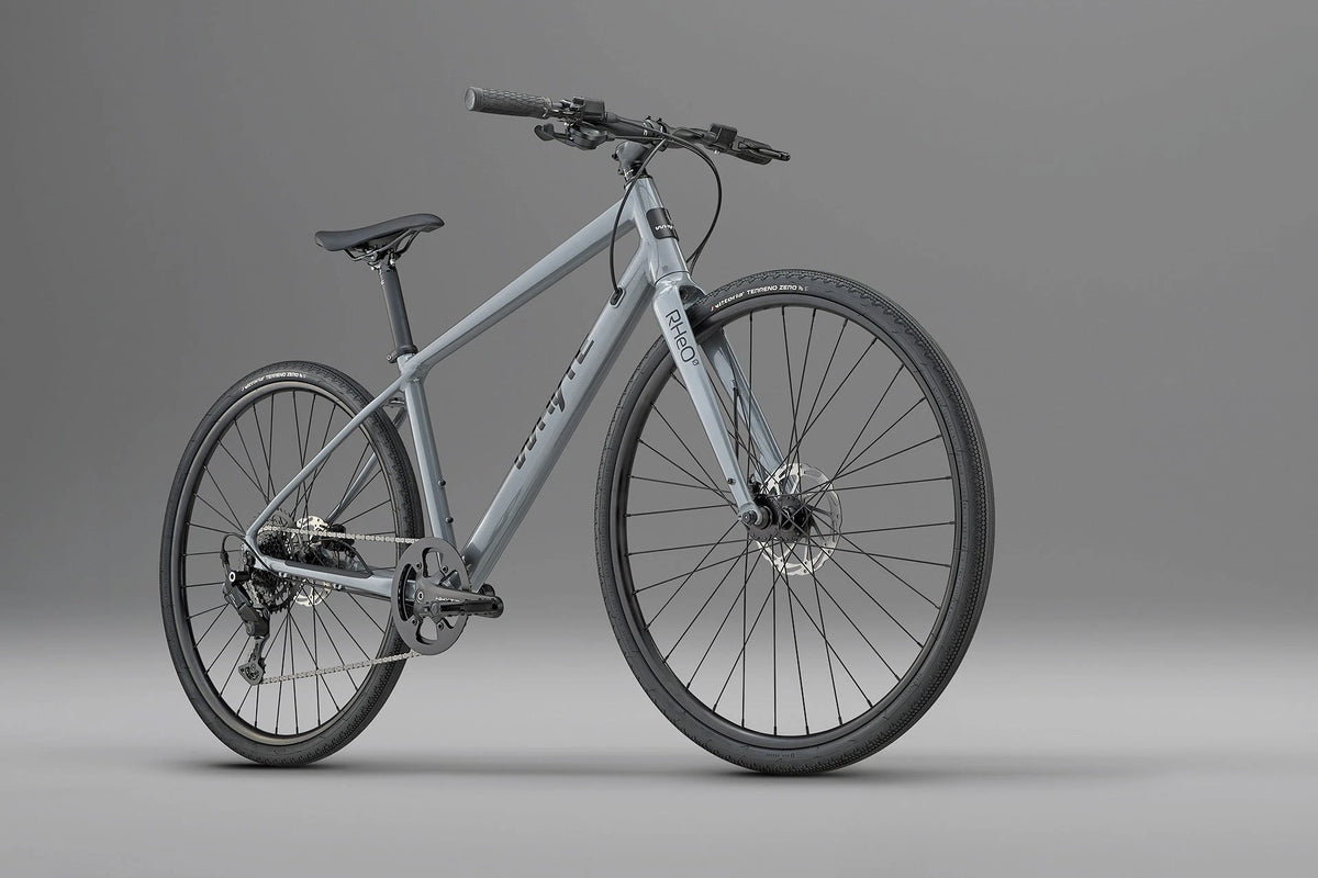 Whyte RHeO 0 hybrid bike in dark silver from a front three-quarter angle, showing the flat bar and front disc brake.